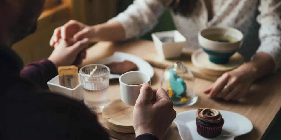 Un homme et une femme attablés dans un café, devant deux tasses et une pâtisserie