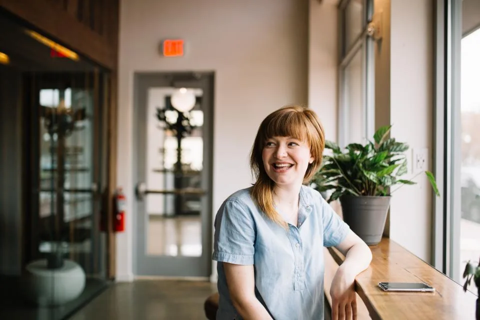Une femme rit, assise dans un café