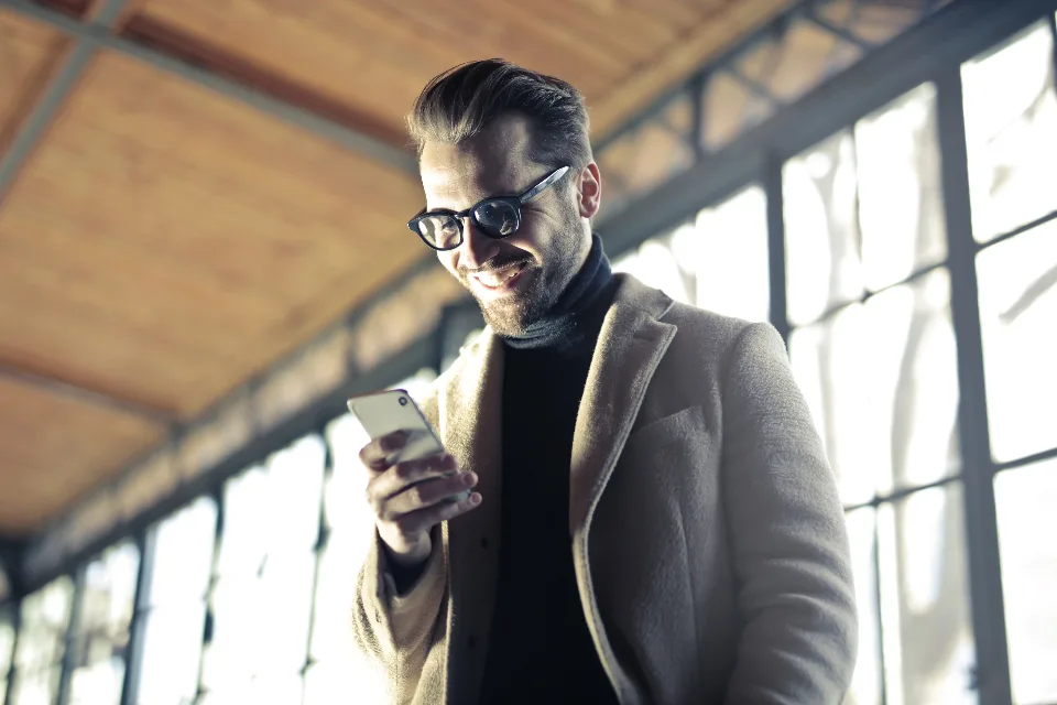 Un homme sourit en lisant un message sur son téléphone