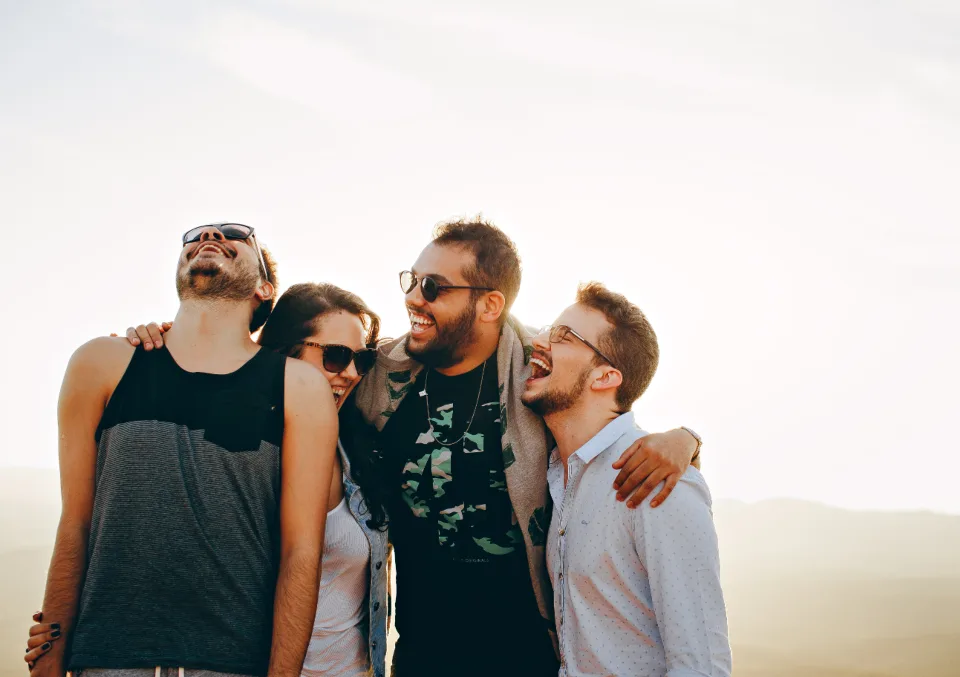 Un groupe d'amis rit en plein air, lunettes de soleil sur le nez